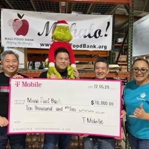 A small group of people holding a donation cheque for Maui Food Bank