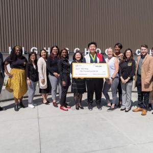 Max Peng with a group of others, holding a large check.