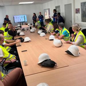 People wearing hi-vis vests sat around a large table 