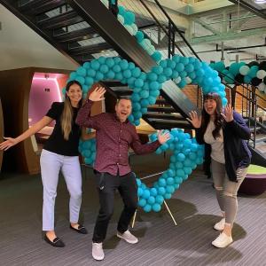 Megan Roder with her GoDaddy team. A heart made out of balloons is shown.