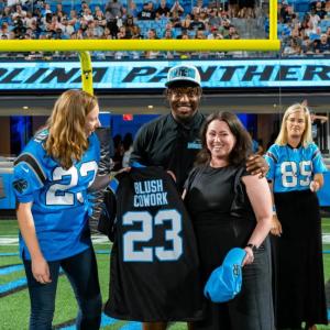 Megan Bornemann holding a custom jersey next to others on a football field.