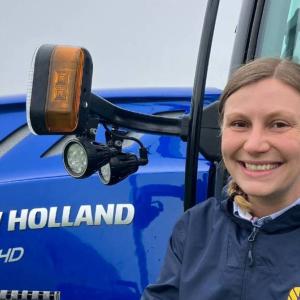 Melody Labinsky outside in front of a large tractor.