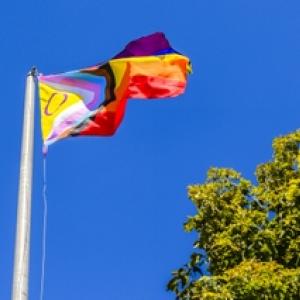 A flag pole with LGBTQ+ flag flying