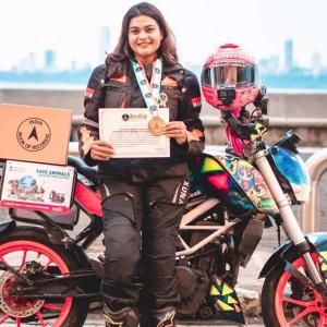 Vishakha Fulsunge standing in front of her motorcycle, wearing a medal and holding a certificate from the India Book of Records