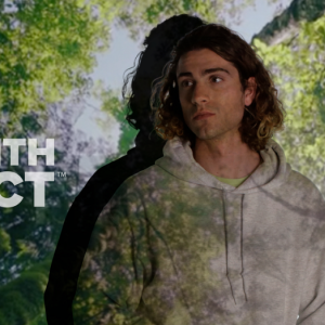 Person stands with forest background. reads: "Gildan, made with respect."