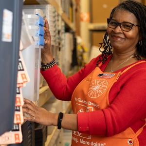 Home Depot associate shown in her store working on restocking a shelf.