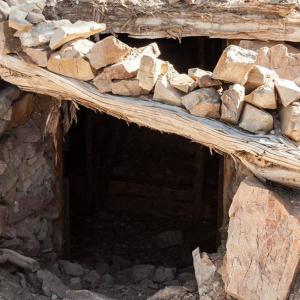 Opening to a mineshaft, rocks and wood create a doorway.