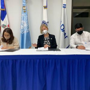 three people signing papers at table
