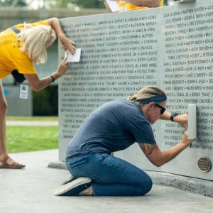 People tracing over names on the Heroes Memorial Park Monument