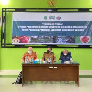 speaker to left; 3 people sitting at desk in front of screen