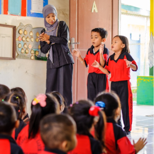 teacher and two students standing in front of sitting class