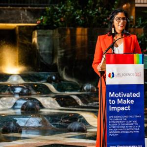 speaker at a lectern with a sign "Motivated to make impact"