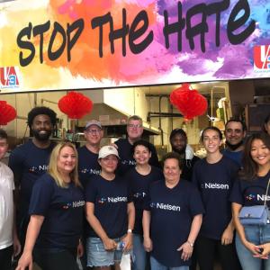A group of people in an Asian restaurant, large "stop the hate" sign