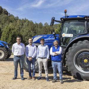 Four people outside standing in front of a new holland tractor
