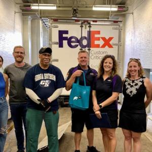 a group standing in front of a FedEx truck