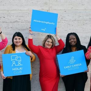NRG women holding signs: equity, women in power, early career success.