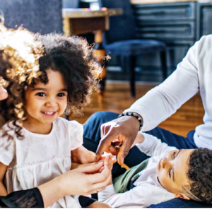 Black family of four seated on the floor of their home.