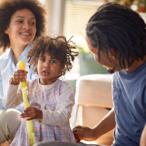 A family seated with their daughter holding a toy.