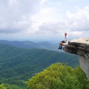 Man seated on the edge of a cliff.