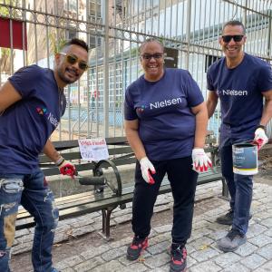 Nielsen NYC volunteers shown painting a bench.