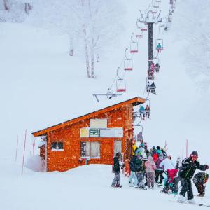 A group of skiers at the bottom of a ski lift and hill on a snowy day.