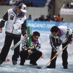 Three people doing a repair on a speed skate track.