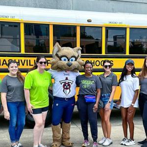 People posed in a line in front of a school bus.