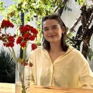 Natalie seated at a table with a vase of red flowers on the table.