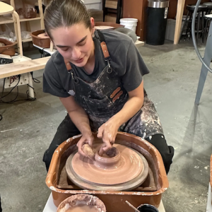 Natalie seated at a potters wheel.