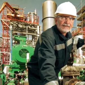 a worker in an industrial setting, cranes and scaffolding in the background