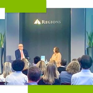 Two people sat on stage in front of an audience 