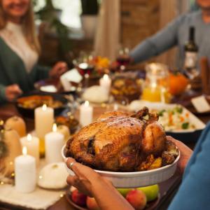 Thanksgiving dinner table with guests and a turkey are shown.