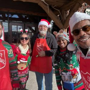 Group of volunteers for The Salvation Army wearing red aprons and santa hats