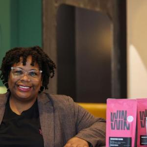 Nikisha Bailey seated next to a display of coffee bags.