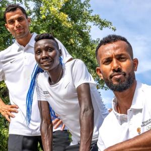 Three people posed from standing to crouched outside.