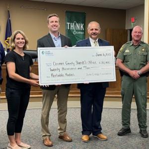 Six people posed, some holding a large check.