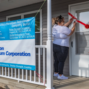 People on a porch opening a door with a ribbon