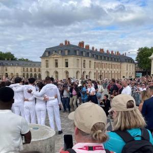 A crowd of people taking photo's of a group of people wearing white Paris 2024 tracksuits