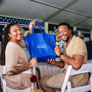 Couple holding up a "Comcast Business" bag at the Operation Shower event 