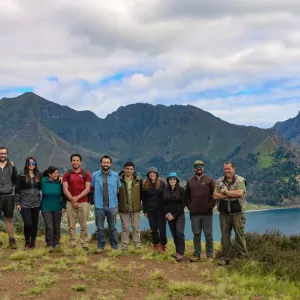 A group of people stood together with mountains in the distance 