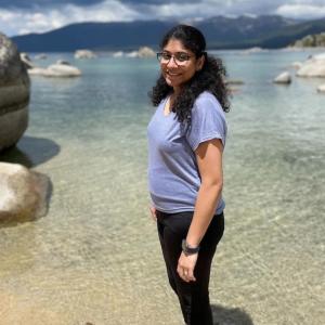 Sanjana standing at the edge of the water at a beach.