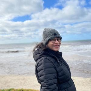 Sanjana on a cold day walking on a beach.