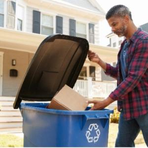 person putting box in recycling bin