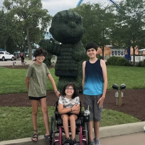 Photo of Alex, Sophia and Maya. Sophia is seated in a wheelchair.