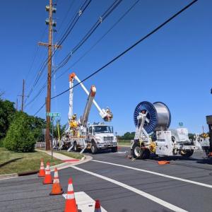 Photo showing PSEG crews updating power lines. Trucks with wiring and a cherry picker are shown.