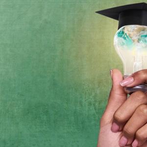 Hand holding a lightbulb with a graduate mitre on top of the bulb.