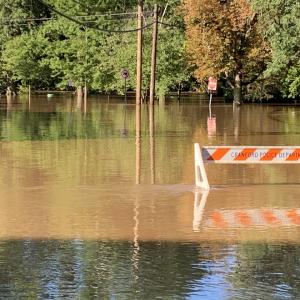 Flooded road with safety hurdle. Safety hurdle is nearly underwater.