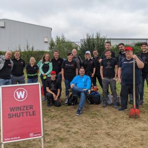 Employees gathered together by Winzer Shuttle sign