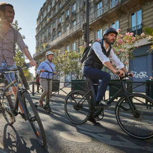Two people on bikes and another on a scooter riding on the road