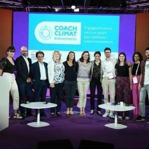 Group of stood together smiling in front of a screen at an event 